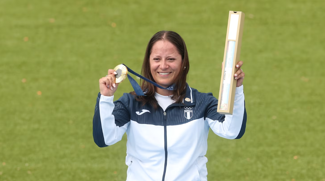 Adriana Ruano celebra la medalla de oro olímpica en foso femenino en París 2024 con la bandera de Guatemala