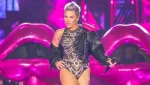 P!nk en un escenario con micrófono, expresión seria, durante un concierto; referencia visual a la polémica con Macklemore y Ed Sheeran por Palestina